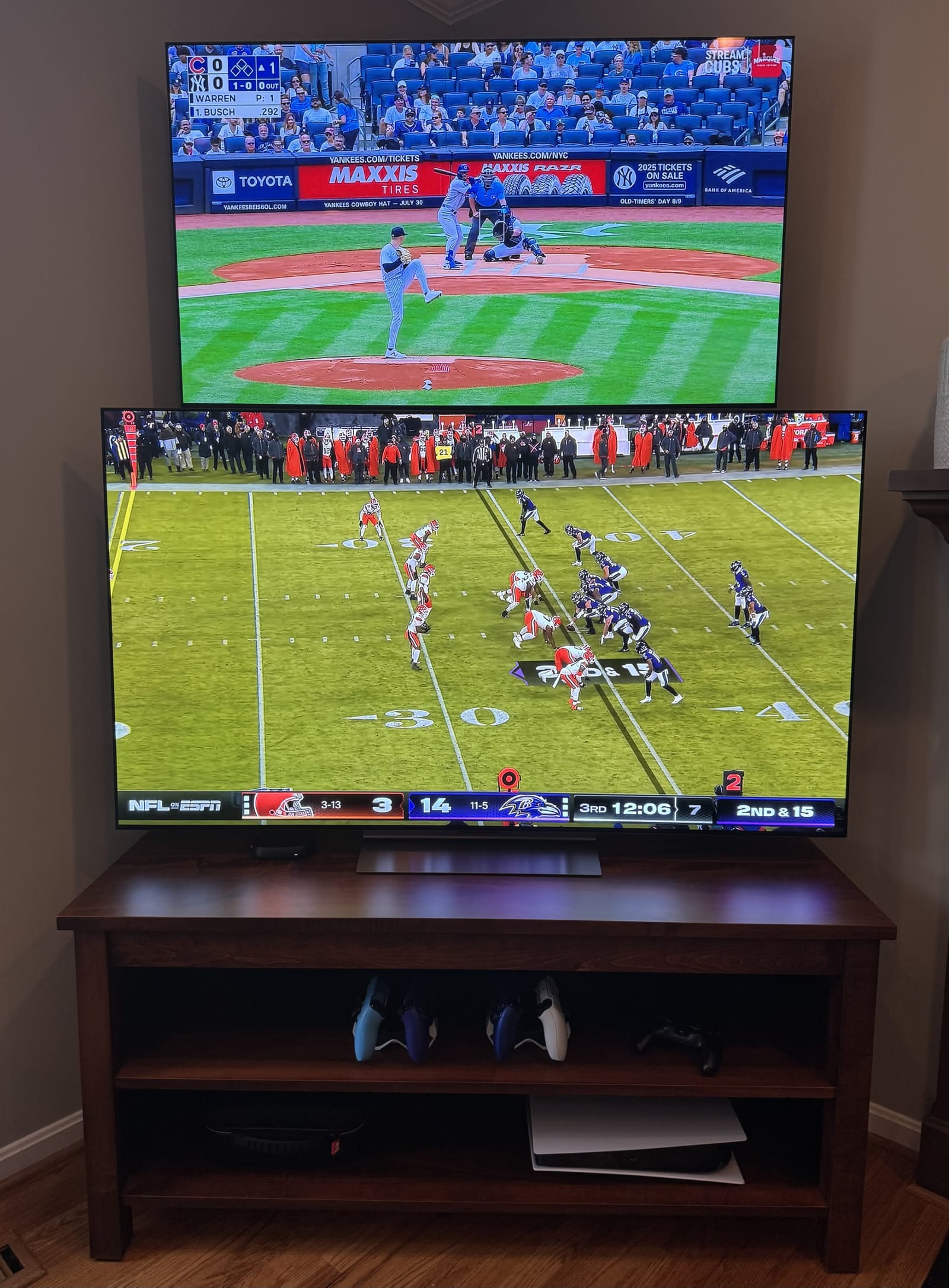 Double TV Stand with two open shelves, both TVs on, in a living room